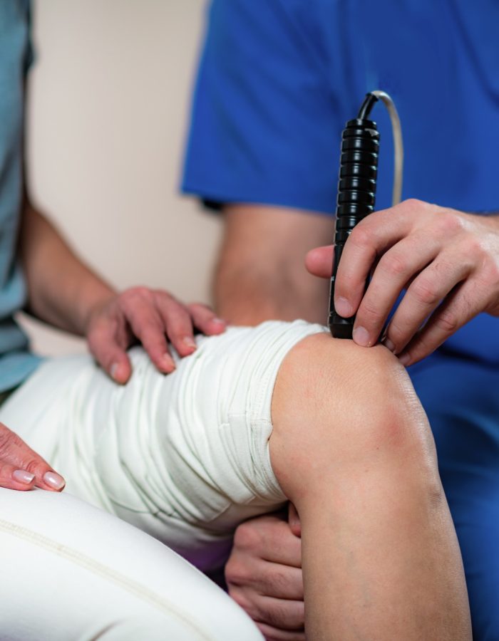Laser Physical Therapy. Physical Therapist Treating Senior Woman's Knee
